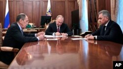 Russian President Vladimir Putin, center, attends a meeting with Russian Foreign Minister Sergey Lavrov, left, and Defense Minister Sergei Shoigu in the Kremlin in Moscow, Feb. 2, 2019. Putin said Russia would abandon the 1987 Intermediate-range Nuclear Forces Treaty