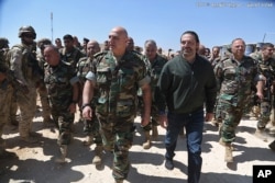 In this photo released by the Lebanese Army official website, Lebanese Prime Minister Saad Hariri, center right, walks with Lebanese Army Commander Gen. Joseph Aoun, center left, during a visit to the command center for the ongoing military operations against Islamic State militants.