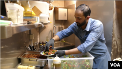 Refugee cook Abdell Baset prepares a Syrian dish for restaurant patrons in Brussels.