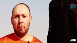 An image grab taken from a video released by the Islamic State (IS) and identified by private terrorism monitor SITE Intelligence Group purportedly shows U.S. freelance writer Steven Sotloff dressed in orange and on his knees in a desert landscape speaking to the camera before being beheaded by a masked militant (R), Sept. 2, 2014. 