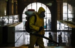 A worker wearing personal protective equipment sprays disinfectant while sanitizing the Kazansky railway station amid the COVID-19 outbreak, in Moscow, Russia, Nov. 2, 2021.