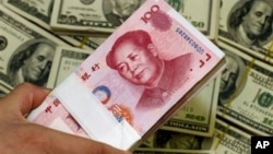 A pack of bills of Chinese yuan next to the U.S. currency