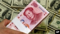 A pack of bills of Chinese yuan next to the U.S. currency