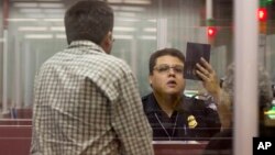 FILE - A Customs and Border Protection officer checks the passport of a non-resident visitor to the United States inside immigration control at McCarran International Airport, Tuesday, Dec. 13, 2011, in Las Vegas. 