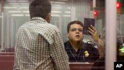 FILE - A Customs and Border Protection officer checks the passport of a non-resident visitor to the United States inside immigration control at McCarran International Airport, Tuesday, Dec. 13, 2011, in Las Vegas. 