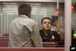 FILE - A Customs and Border Protection officer checks the passport of a non-resident visitor to the United States inside immigration control at McCarran International Airport, Tuesday, Dec. 13, 2011, in Las Vegas. Iraq, Iran, Libya, Yemen, Syria, Somalia and Sudan are the countries affected affected by what the administration of President Donald Trump has touted as a temporary travel ban.