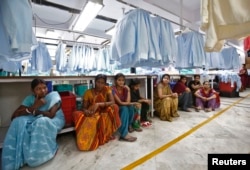 FILE - Employees sit during their lunch time inside a textile mill in India, April 16, 2014.