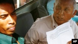 Chum Mey, right, a former S-21 prison survivor, sits in a pickup truck before joining a rally demanding Kem Sokha, vice president of the Cambodia National Rescue Party (CNRP), to apologize for allegedly saying that exhibits at a Khmer Rouge-era genocide museum in Phnom Penh were faked, in front of the party's office, in Phnom Penh, Cambodia, Sunday, June 9, 2013. Cambodia's main opposition party denounced the large demonstration in the capital Sunday, which they said was staged by supporters of Prime Minister Hun Sen to intimidate rivals ahead of July elections. (AP Photo/Heng Sinith)