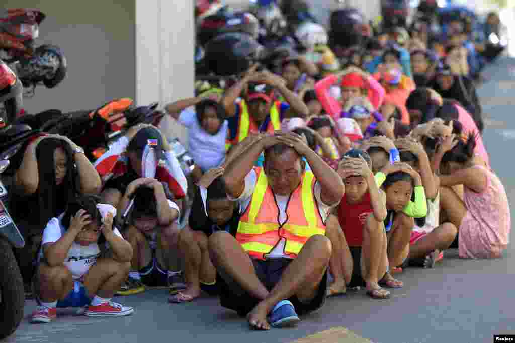 Residents cover their heads with their hands during a simultaneous earthquake drill inside the police headquarters in Quezon city, metro Manila.
