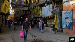 People walk underneath the banners of Fatah and the Palestinian flags inside the Bourj al-Barajneh Palestinian refugee camp in Beirut, Lebanon, May 4, 2017.