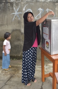 Seorang ibu memasukan surat suara ke dalam kotak suara dalam pelaksanaan pilkada Tangerang, Banten, 27 Juni 2018. (Foto: AFP)