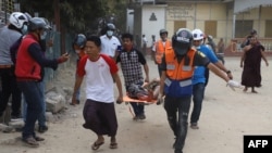 A wounded man is carried on a stretcher by a medical team after security forces opened fire on protesters during a demonstration against the military coup in Mandalay on February 20, 2021. (Photo by str / AFP)