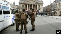 Belgian soldiers stand guard next to one of the memorials to the victims of the recent Brussels attacks, at the Place de la Bourse in Brussels, March, 27, 2016. 