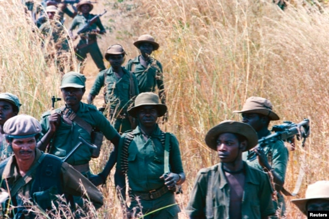 FILE - UNITA troops walk through a field, 20 miles from the front line, at Munhango, Angola, April 29, 1986. The UNITA forces, led by Jonas Savimbi, were engaged in a guerilla war against the Angola government.