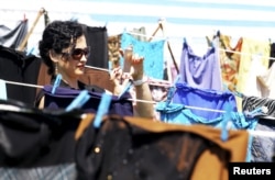 Kosovo artist Anisa Ismailji takes a picture with her mobile phone at an art installation of women's dresses, named "Thinking of You" by Kosovo-born, London-based artist Alketa Mrripa-Xhafa, in Pristina, Kosovo, June 12, 2015. Dresses and skirts donated by Cherie Blair and Rita Ora were among 5,000 pegged to clotheslines in a Kosovo stadium in the exhibit, aimed at drawing attention to the stigma suffered by victims of wartime sexual violence.