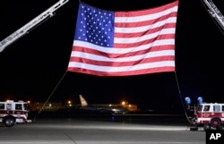 A U.S. government plane, seen in the background below the flag, carrying three Americans freed from captivity in North Korea arrives at Andrews Air Force Base, Md., May 10, 2018.