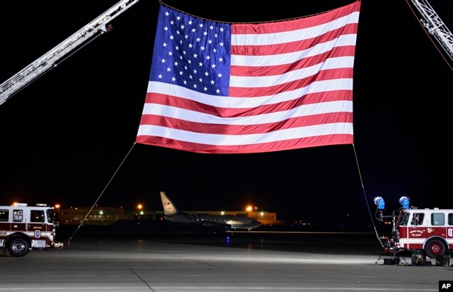 A U.S. government plane, seen in the background below the flag, carrying three Americans freed from captivity in North Korea arrives at Andrews Air Force Base, Md., May 10, 2018.