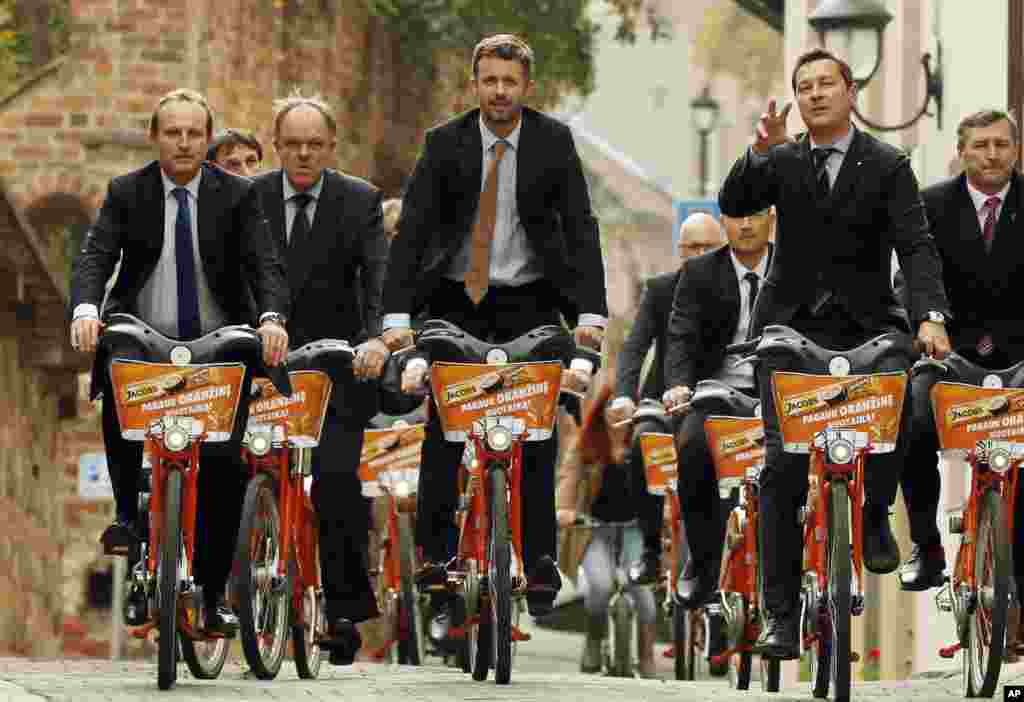 Denmark's Crown Prince Frederik, center, Danish Minister for Climate, Energy and Building Martin Lidegaard, left, and Vilnius mayor Arturas Zuokas, right, cycle around the old city during a sightseeing tour in Vilnius, Lithuania. 