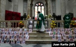 Barisan foto dari perempuan yang meninggal akibat menjadi korban kekerasan terpampang di altar Gereja Katedral di La Paz, Bolivia, pada 25 November 2021, sebagai bagian dari peringatan Hari Anti Kekerasan Terhadap Perempuan. (Foto: AP/Juan Karita)