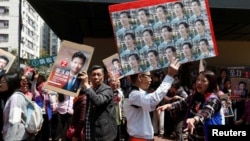 A supporter carrying photos of pro-democracy candidate Edward Yu walks past a supporter of Vincent Cheng from Democratic Alliance for the Betterment and Progress of Hong Kong, March 11, 2018. 
