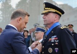 El teniente general Ben Hodges, comandante del ejército estadounidense en Europa, a la derecha, es condecorado con la Cruz del Comandante con una Estrella de la Orden del Mérito por el presidente polaco, Andrzej Duda (izquierda), antes del desfile militar anual que celebra al ejército polaco, en Varsovia, el 15 de agosto de 2017.