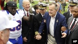 Mantan Presiden AS George H.W. Bush dipapah saat menghadiri sebuah pertandingan sepakbola di Houston, Texas (4/11). (AP/Dave Einsel)