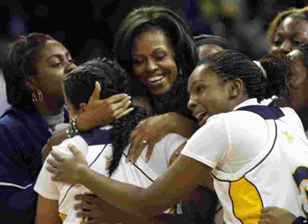 First Lady Michelle Obama, center, embraces members of the Johnson C. Smith ladies' basketball team during a "Let's Move!" physical fitness promotion between games at the CIAA basketball tournament in Charlotte, N.C. on Friday, March 2, 2012. (AP Photo/N