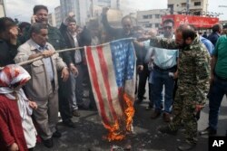 ABŞ-ın İnqilabi Qvardiyanı terrorçu təşkilat elan etməsindən sonra etirazçılar ABŞ bayrağının maketini yandırır. Tehran, İran, 12 aprel, 2019.
