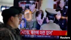South Korean soldiers walk past a television showing reports on the execution of Jang Song Thaek, who is North Korean leader Kim Jong Un's uncle, at a railway station in Seoul on December 13, 2013.