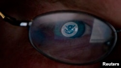 FILE - The logo of the U.S. Department of Homeland Security is reflected in the spectacles of an analyst working in a watch and warning center of a cyber security defense lab in Idaho, Sept. 29, 2011. 