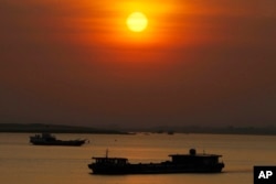 FILE - A dredging river barge, foreground, carries sand in the middle of Mekong River near Phnom Penh, Cambodia, Friday, Jan. 24, 2020. (AP Photo/Heng Sinith)