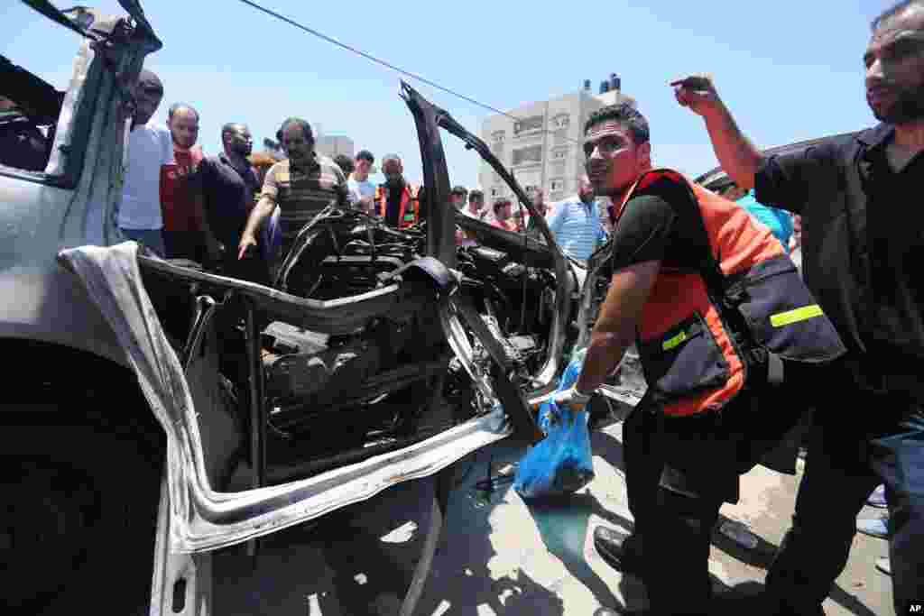 Palestinians gather around a destroyed car after an airstrike in Jabalya refugee camp in the north of the Gaza Strip, July 10, 2014.