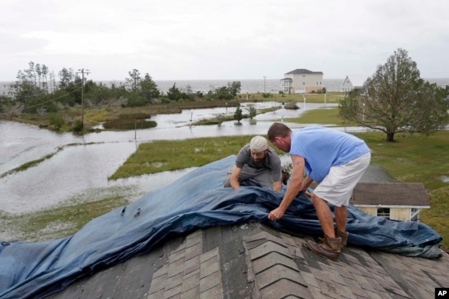 Jeff Pyron, left, and Daniel Lilly cover Lilly's roof after Tropical Storm Florence hit Davis, N.C., Sept. 15, 2018. The town had 4½ feet of storm surge.