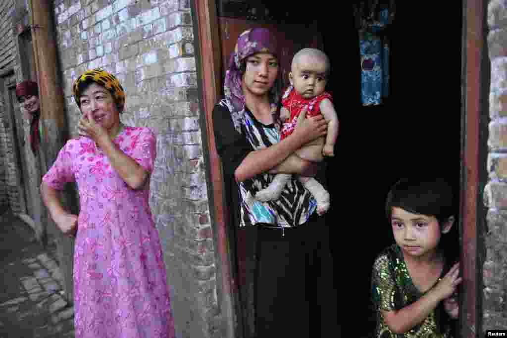 زنی از قوم اویغور در آستانه در خانه، همراه با فرزندانش -کاشغر، ۲۲ ژوئیه ۲۰۱۲