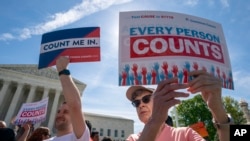 Imigran ki t ap manifeste devan Kou Siprèm nan pandan gran jij yo t ap fè deba sou plan Prezidan Trump genyen pou l mete kesyon nasyonalite nan fòm sou resansman an. (Washington, 23 avril 2019)..