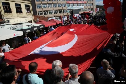 FILE - People carry the Turkish flag as Turkish President Recep Tayyip Erdogan and his Serbian counterpart, Aleksandar Vucic, visit Novi Pazar, Serbia, Oct. 11, 2017.