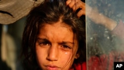 Anak perempuan asal Suriah yang terpaksa mengungsi akibat operasi militer Turki di timur laut Suriah, menangis di bus yang membawanya ke kamp Bardarash, utara Mosul, Irak, 16 Oktober 2019. 