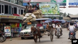 Vehicles make their way on a road near local bazaar in Mawlamyine, Mon State, Burma, March 11, 2011.