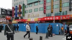 Chinese guards stand at the entrance of the pedestrian Wangfujing area in Beijing. The blue metal barriers are part of a construction site that partially blocks a designated spot for anti-government protests, February 25, 2011.
