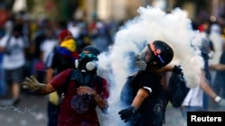 An anti-government protester throws a gas canister at the police during clashes at Altamira Square in Caracas, Venezuela, March 3, 2014.