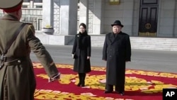 Imagen tomada de la televisión de Kim Jong Un y su esposa, en un desfile militar en Pyongyang.