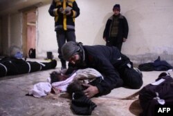 A man weeps over his child at a make-shift morgue in Douma who was killed in air strikes on the Syrian village of Mesraba in the besieged Eastern Ghouta region on the outskirts of the capital Damascus, Feb. 19, 2018.