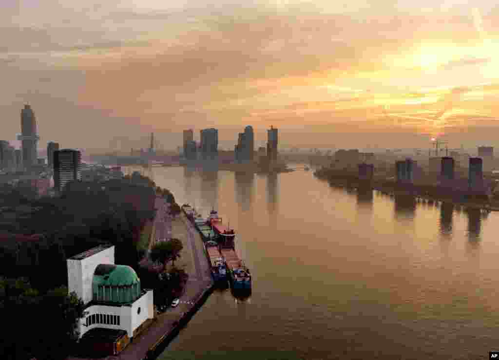 The sun rises over the city of Rotterdam, Netherlands, on a misty Sunday morning.