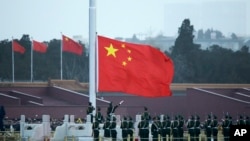 FILE - Chinese paramilitary policemen perform a flag raising ceremony on Tiananmen Square in Beijing, March 5, 2016.