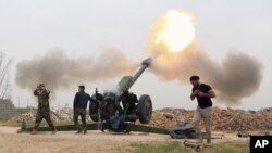 FILE - Iraqi security forces fire at Islamic State militants positions from villages south of the Islamic State group-held city of Mosul, Iraq.