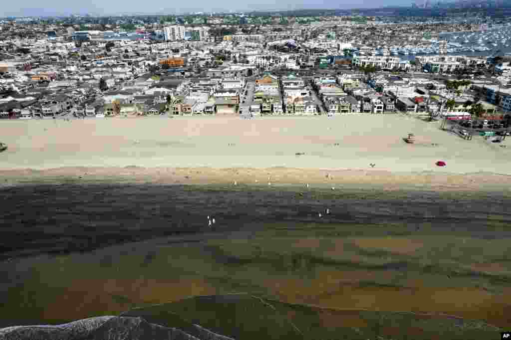 In this aerial image taken with a drone, workers in protective suits clean the contaminated beach after an oil spill in Newport Beach, California, Oct. 6, 2021.