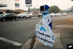 A man, who usually advertises a computer repair store, holds up a sign thanking firefighters working on the Carr Fire, Aug. 13, 2018, in Redding, California.