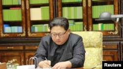 This image made from video of a news bulletin aired by North Korea's KRT on Nov. 29, 2017, shows an image of North Korea's leader Kim Jong Un signing what is said to be a document on Nov. 28, 2017, authorizing a missile test.