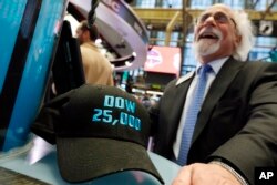 FILE- Trader Peter Tuchman smiles as he poses with an old "Dow 25,000" hat on the New York Stock Exchange trading floor, Jan. 30, 2019.