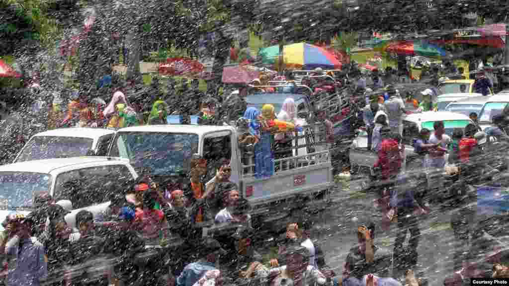 People on a truck react after being splashed with water while others shoot back using water guns during the traditional Burmese water festival on Pyi Road in Rangoon, Burma, April 16, 2014. (MoeMoe Htun/VOA).